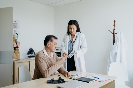 Inside the clinic, a female doctor discusses medical test results with a male patientjpg